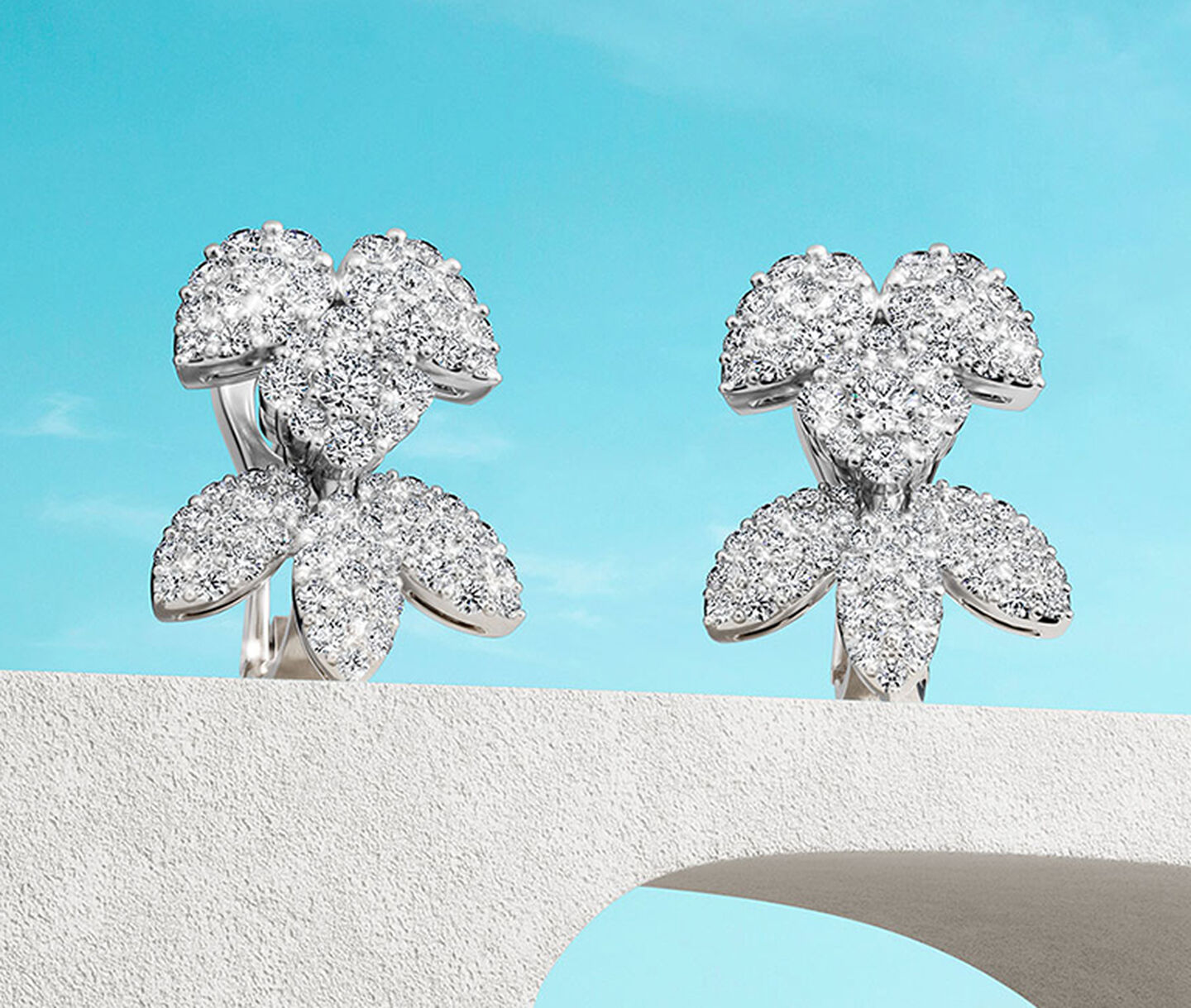 Birks Snowflake diamond earrings on a blue background.